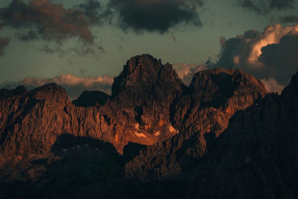 Mountains are lit with warm sunlight under cloudy skies.
